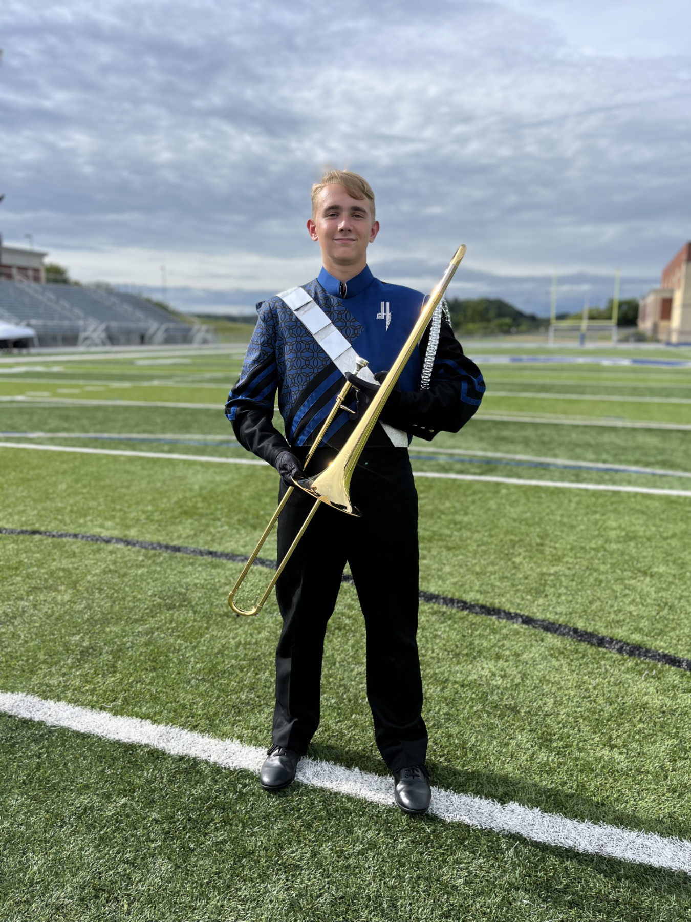 Eli holding the trombone in his marching band uniform.